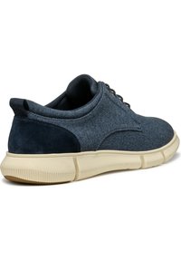 Sneaker blu scuro con tomaia in tessuto testurizzato, caratterizzato da un accento in suede sul tallone e una spessa suola in gomma beige con dettagli scanalati.