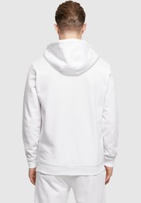 Witte hoodie met een kangoeroezak en ribgebreide manchetten. Zachte stof met een relaxte pasvorm, met een gestikte zoom en een neklijn aan de achterkant.