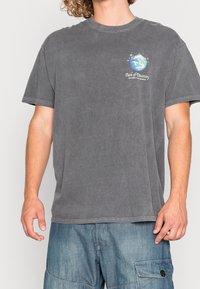 Šedé bavlněné tričko s kulatým výstřihem, krátkými rukávy a barevným motivem Země s textem na levé části hrudi.