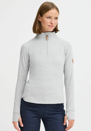 Light gray, long-sleeve zip-up pullover with a high collar, featuring a wooden zipper pull and logo patch on the left arm. Soft texture.