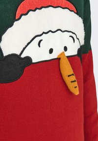 Roter und grüner Strickpullover mit einem Schneemann-Motiv, ausgestattet mit einem Filzhut, schwarzen Akzenten und einer orangen gestrickten Karotten-Nasendetail.