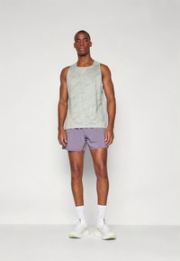 Helerohelist meremustriga tank-top, mida kantakse lilla lühikeste pükstega. Kandmiseks on valged spordisokid ja tossud, rõhutades mõnusat lõdvestunud stiili.