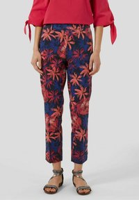 Blomstrede bukser i marineblå med røde og blå tropiske blomster mønstre, slim fit, kort længde, blødt stof, parret med sølv sandaler.