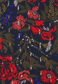Tecido floral com grandes flores vermelhas e azuis, acompanhadas de folhas verdes sobre um fundo azul marinho escuro, realçado por detalhes e padrões em tons dourados.