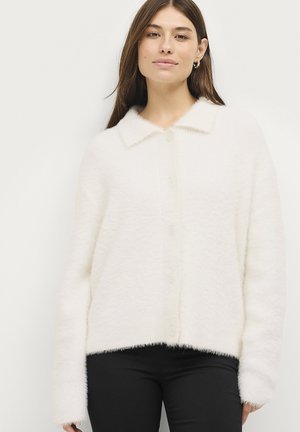 Witte donzige cardigan met een kraag, knopen aan de voorkant en lange mouwen, met een tekstuurstof en een cropped zoom. Gekocht over een zwarte broek.