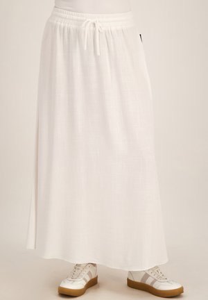 Lange witte rok met elastische tailleband en trekkoord, gedragen met witte sneakers met rubberzolen en gestreepte details.