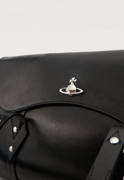 Sac en cuir noir avec un emblème sphérique argenté présentant une croix et un détail d'anneau sur le rabat, avec des coutures visibles et des sangles.