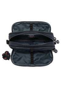 Pochette zippée bleu marine avec deux compartiments, extérieur en nylon lisse, intérieur doublé et charm de singe porte-clés attaché.