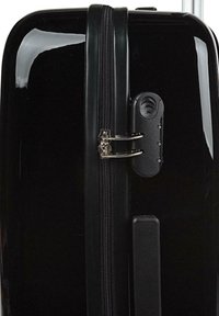 Maleta rígida negra con cierre de cremallera, candado metálico y un mango texturizado para un agarre fácil. Superficie suave y brillante.