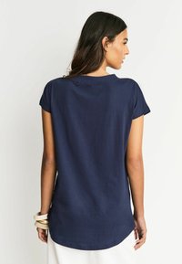 Granatowy bawełniany t-shirt, krótkie rękawy, zaokrąglony dół, prosty wzór, minimalne przeszycia na kołnierzu i rękawach.