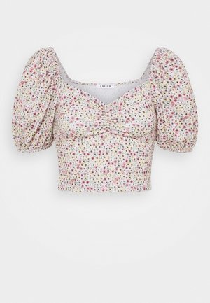 Top court floral avec de courtes manches bouffantes ; comportant un décolleté carré et un centre froncé ; les couleurs incluent le rose, le jaune et le blanc sur un fond clair.