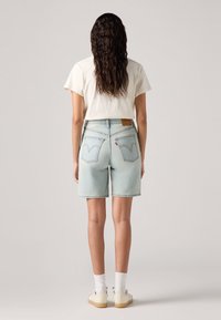 Ανοιχτό μπλε τζιν σορτς με ψηλή μέση, πίσω τσέπες με ραμμένο σχέδιο και δερμάτινη ετικέτα μάρκας σε καφέ χρώμα στη μέση.