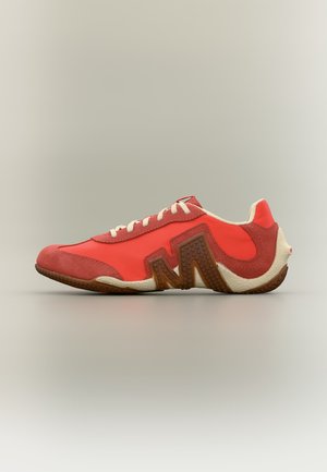 Chaussure de sport rouge avec des lacets blancs, une semelle marron texturée et un grand détail marron "M" sur le côté, sur un fond neutre.