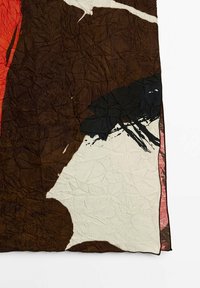 Tessuto testurizzato con un motivo astratto marrone, crema e rosso; presenta una superficie increspata e bordi irregolari per un design unico.