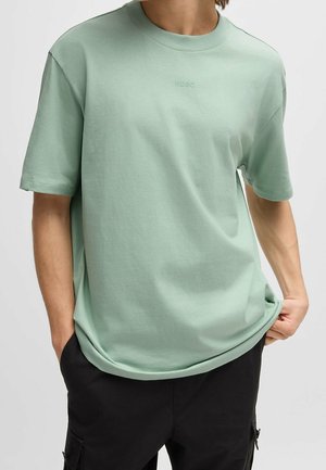 T-shirt vert menthe en coton doux, doté d'un col rond, de manches courtes et d'un logo "HUGO" brodé discret sur la poitrine.