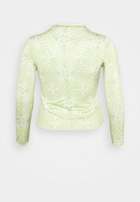 T-shirt de manga longa em verde claro com um padrão floral e geométrico em branco. Feita de um tecido suave com uma silhueta ajustada e decote redondo.