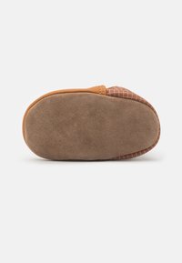 Brązowe zamszowe buty wsuwane z teksturowaną cholewką i gładką podeszwą, charakteryzujące się płaskim profilem i zaokrąglonym noskiem.