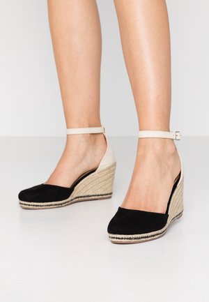 Černé semišové platformové sandály s juta podrážkou, vybavené páskem kolem kotníku a světlým zadním dílem. Hladký povrch a otevřený design paty.