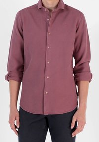 Camicia a maniche lunghe con bottoni di un profondo colore rosa, caratterizzata da un tessuto testurizzato, un logo sottile sul petto e maniche arrotolate.
