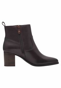 Stivaletto in pelle marrone con punta affilata, cerniera laterale e tacco in legno impilato. Texture liscia con dettagli di cucitura sottili.
