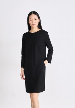 Zwarte jurk met lange mouwen, ronde halslijn, knielange snit en zijzakken. Gemaakt van soepele stof met een minimalistisch ontwerp.