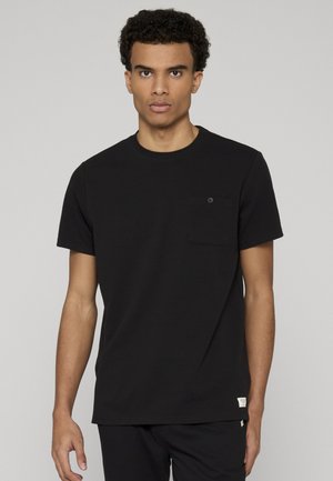 Schwarzes T-Shirt mit kurzen Ärmeln aus strukturiertem Stoff, rundem Ausschnitt und einer kleinen Brusttasche mit Knopfdetail.