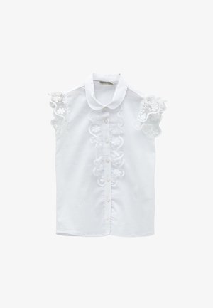 Biała, bezrękawnikowa bluzka z falbankowymi kwiatowymi koronkowymi ramionami, zapinana na guziki z przodu i zaokrąglonym kołnierzykiem.