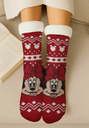 Rote Socken mit weißen Mustern, die ein Cartoon-Gesicht mit einer Schleife zeigen. Die Bündchen sind flauschig weiß. Stricktextur mit festlichen Designelementen.
