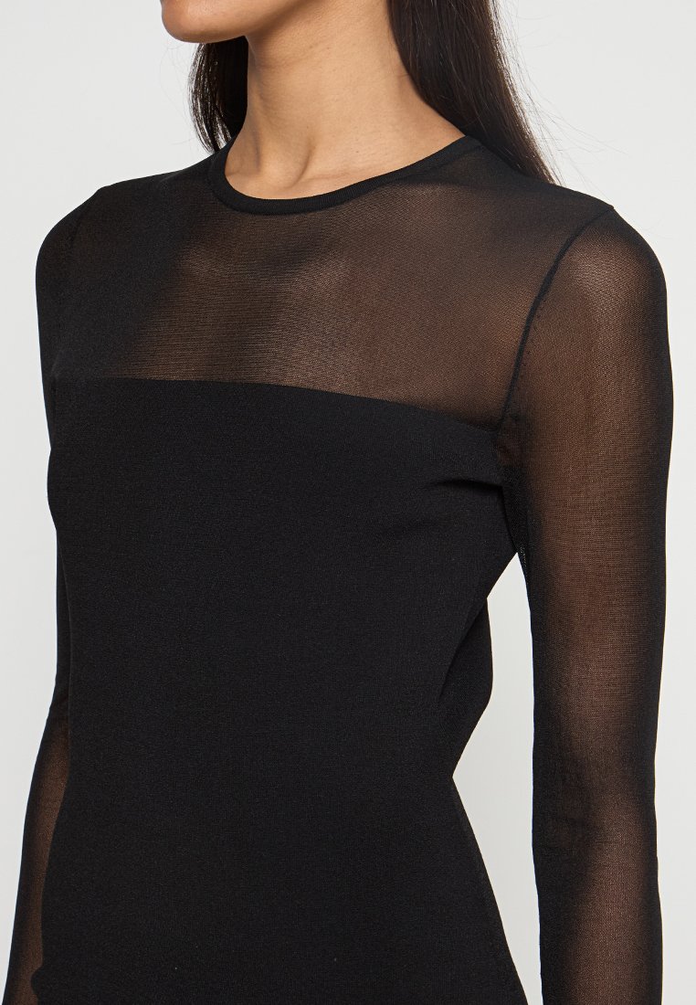 Haut à manches longues noir avec un panneau en mesh transparent aux épaules et sur la poitrine, doté d'un design de corsage lisse et ajusté.