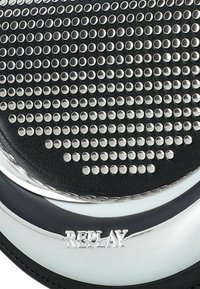 Schwarze Lederoberfläche mit mehreren Reihen kleiner silberner Nieten über einer glänzenden, metallischen, gebogenen Platte, die mit "REPLAY" graviert ist.