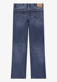 Bakifrån vy av blå denimjeans med två bakfickor, orange sömnadsdetaljer och läderpatch med Levi's märke på midjan.