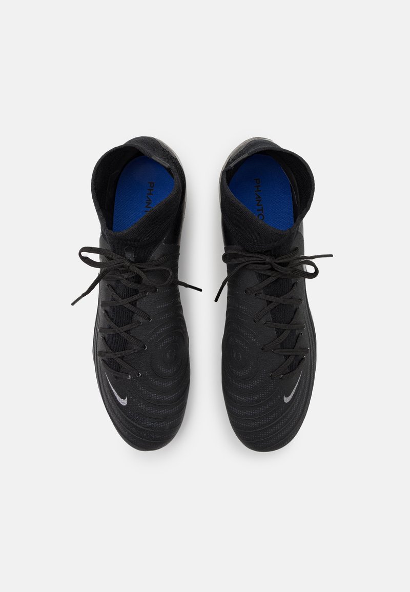 Botas de fútbol negras con parte superior texturizada, patrones circulares y cordones. Tienen una plantilla azul y un pequeño logo plateado en el lateral.