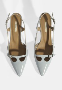 Helles blaues Lackleder-Slingback mit spitzem Zehenbereich, offenen Ausschnitten, seitlichen Schnallen und einer glatten, hellbraunen Innensohle.