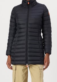 Černá prošívaná péřová bunda s vertikálním prošíváním, vysokým límcem, předním zipem a oranžovým jezdcem. Hladká textura a lehký materiál.