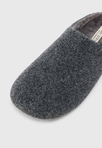 Pantofole di lana grigia con una superficie morbida e testurizzata e una punta arrotondata; presentano un design slip-on e un rivestimento interno soffice.
