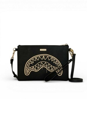 Borsa a tracolla rettangolare nera con zip e tracolla dorate, con un disegno dorato astratto di una bocca dentata sulla parte anteriore.