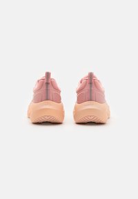 Pair of pink athletic sneakers viewed from the back, showing thick chunky soles and pull tabs with a checkered pattern.
