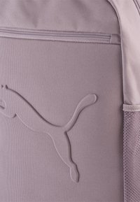 Paarse stoffen rugzak met een gestructureerd Puma-logo, ritssluiting en een mesh zijvak voor extra opbergruimte.