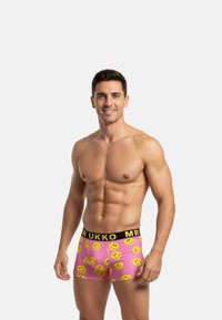 Calzoncillos boxers rosa colorido con patrones de caritas sonrientes amarillas, cinturilla elástica negra con el texto "MR RUKKO", diseño ajustado.