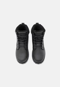 Crne čipkaste čizme s glatkom kožnom vanjštinom i mekanim crnim podstavom. Debeli gumeni potplat za prianjanje. Uključuje dizajn s okruglim vrhom.