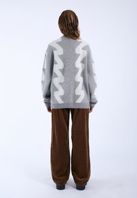 Gray knitted sweater with a white zigzag pattern, paired with brown corduroy wide-leg pants. The outfit features a relaxed fit and ribbed cuffs.