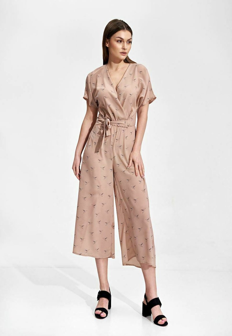 Różowy kombinezon wykonany z lekkiej tkaniny, z krótkimi rękawami, z wiązaniem w talii, szerokimi nogawkami i subtelnym wzorem ptaków. Noszony z czarnymi szpilkami.
