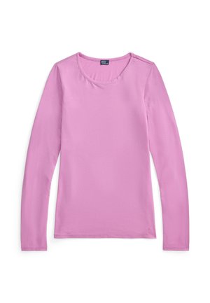 Kobieta w dopasowanym, różowym topie z długim rękawem oraz różowo-białych, paskowanych szortach z widocznym paskiem Polo Ralph Lauren.