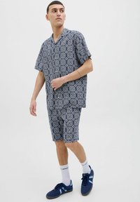 Laiva sininen lyhythihainen paita ja siihen sopivat shortsit, joissa on geometrinen valkoinen kuvio. Asusteessa on rento istuvuus ja kaulusdesign.