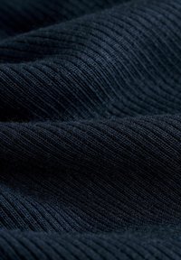 Dunkelblauer, strukturierter Stoff mit einem gerippten Muster, der weiche Fasern und einen glatten Fall aufweist und Licht- und Schattenspiele in den Falten zeigt.