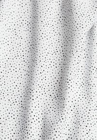 Tela blanca con una textura fina que presenta un patrón uniforme de pequeños puntos negros a lo largo.