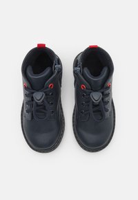 Mörkblå läderstövlar med röda detaljer, elastiska snören och sidodragkedjor. Rundad tå, vadderad insida, texturerad sula och sömdekoration.