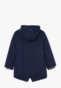 Abrigo de invierno azul marino con capucha y mangas largas, visto desde atrás, con botones a presión en la capucha y un dobladillo recto con una pequeña abertura central.