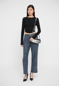 Black cropped long-sleeve top, blue textured wide-leg pants with sparkly accents, and black pointed-toe heels, paired with a silver handbag.