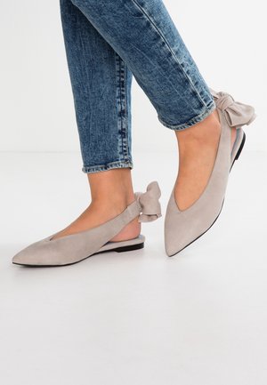 Szare zamszowe baleriny na obcasie typu slingback z ostrym noskiem, ozdobione kokardą przy pięcie i niską czarną podeszwą. Noszone z niebieskimi dżinsami.